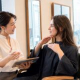 外国人客の希望する髪型を英語で確認する日本人美容師