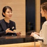 外国人宿泊客へ英語でチェックイン案内をする日本人ホテルスタッフ