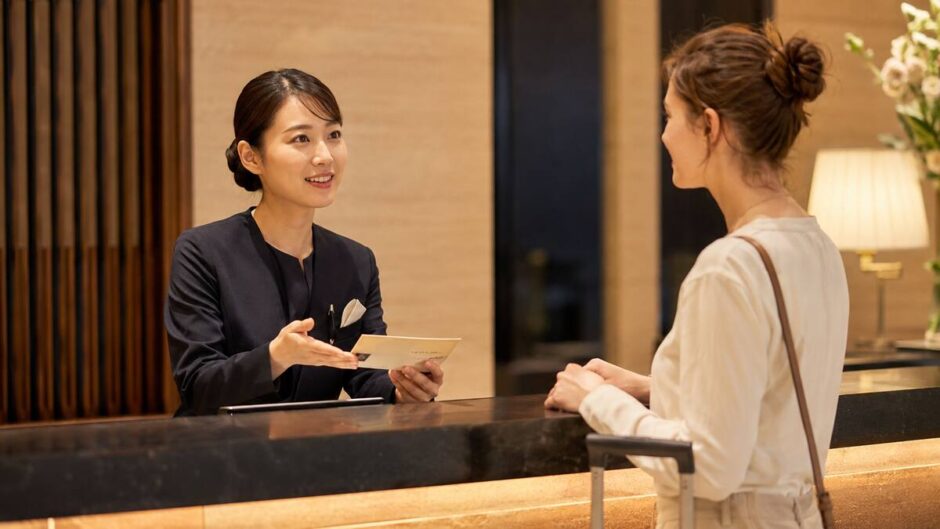 外国人宿泊客へ英語でチェックイン案内をする日本人ホテルスタッフ