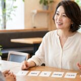 中学レベルの英単語カードを使ってカフェで会話する大人の女性