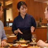 外国人客に英語で料理を説明する日本人飲食店スタッフ
